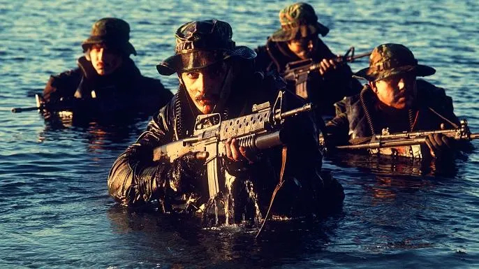 A squad of United States Navy SEALs trudging through water, circa 1986. 